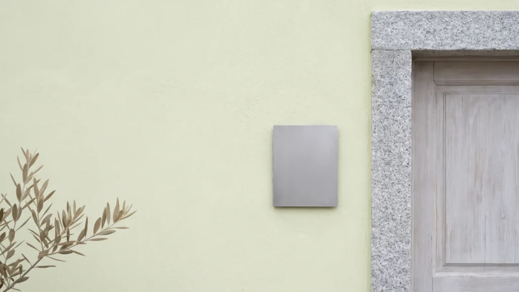 Citofono metallico minimale accanto alla porta di un ingresso con stipite in granito